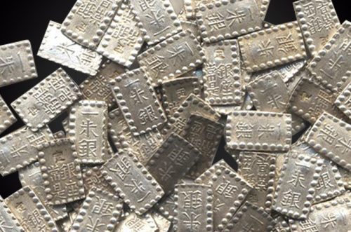 Handfuls of Pieces of Samurai Ingot Silver Against a Black Background